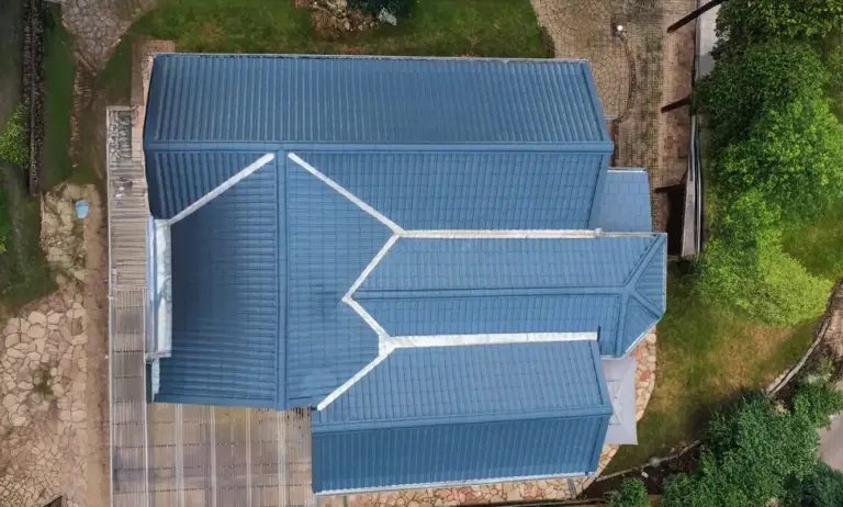 Ein Foto eines anthrazitfarbenen Daches von oben, rundherum ein Garten.